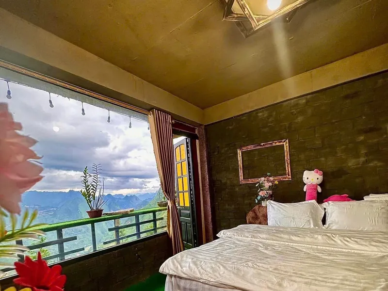 A bedroom at Aladin homestay in Dong Van, bed made up with a mountain view through the open balcony door