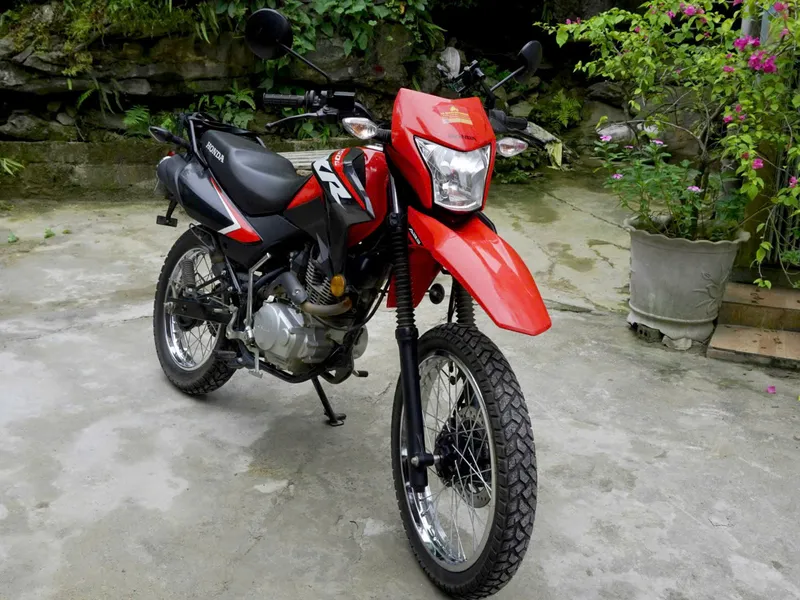 A red Honda XR enduro motorbike parked in a courtyard, ready for rental in Ha Giang