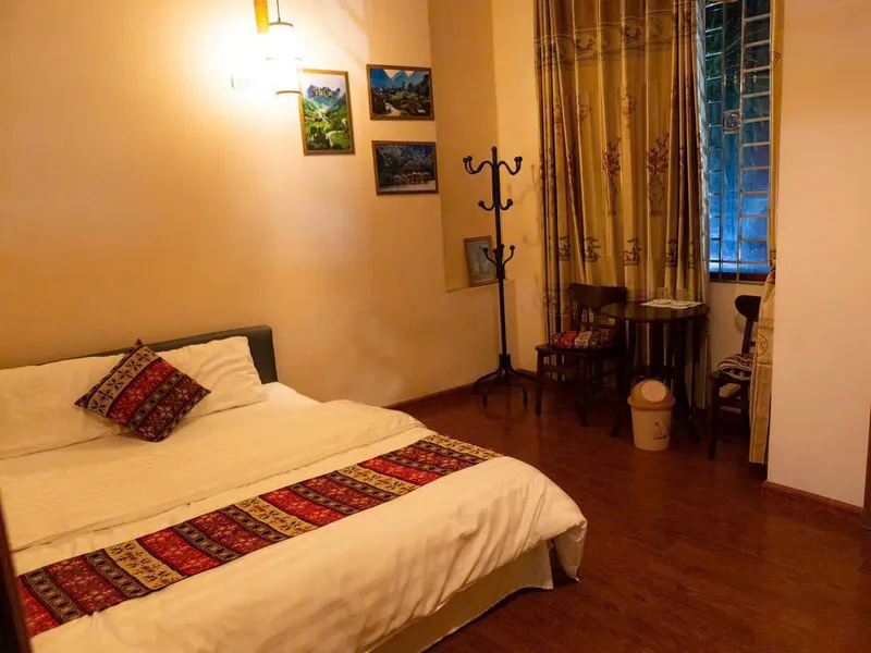 A quiet room at Su Hotel in Ha Giang city, dark wood floor and framed prints of the mountains
