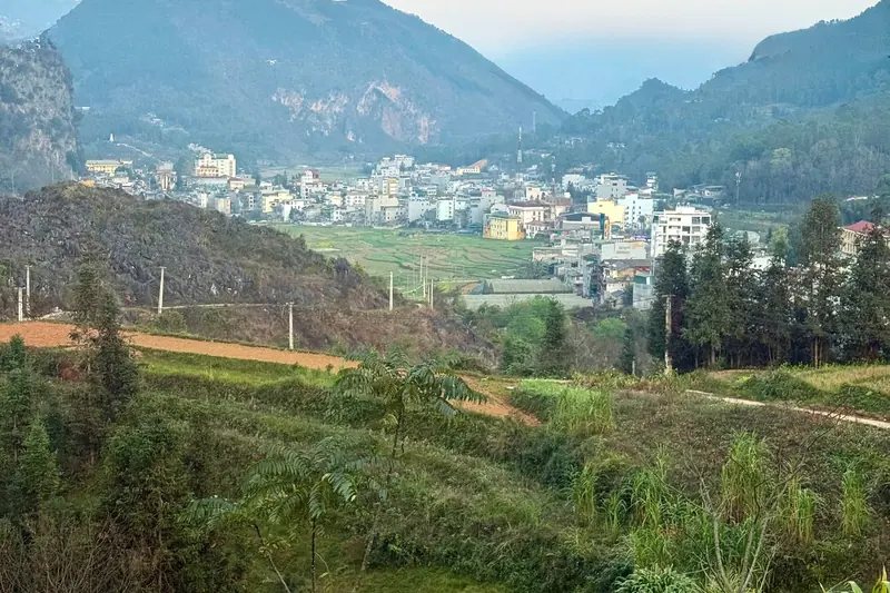 Dong Van town seen from the hillside at dusk, ringed by karst mountains